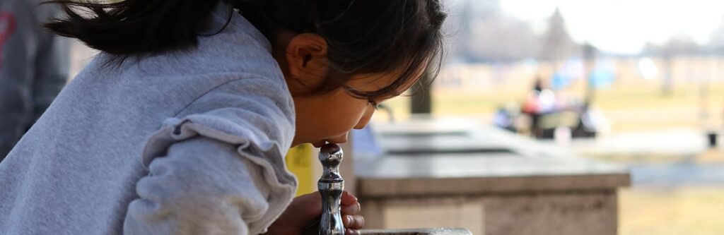 A child drinking from a water fountain