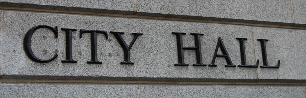 Image of a stone wall with "City Hall" signage