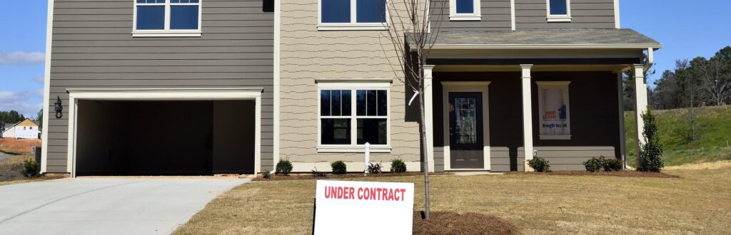 Home with for sale/under contract signage in yard